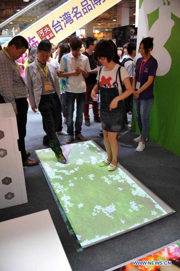 People experience a carpet with a touch-screen at the 2013 Taiwan Trade Fair in Shijiazhuang, capital of north China's Hebei Province, May 16, 2013. The four-day fair attracting more than 180 enterprises from southeast China's Taiwan kicked off here on Thursday. (Xinhua/Zhu Xudong)