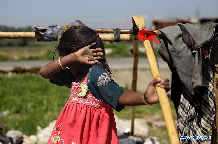 A Hindu girl shies away from the camera at a slum area near Bijbehara town of Anantnag district, around 44 km south of Srinagar city, the summer capital of Indian-controlled Kashmir, May 16, 2013. Thousands of poor Hindu labourers from Indian states migrate to Indian-controlled Kashmir during summers to escape the scorching heat and earn their livelihood by either doing menial jobs or selling brooms. (Xinhua/Javed Dar)