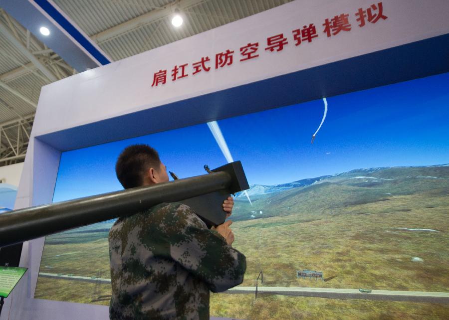 An assistant demonstrates a simulated shoulder-fired anti-aircraft missile during a science exhibition in Beijing, capital of China, May 19, 2013. The exhibition is a part of the National Science and Technology Week and will last till May 25. (Xinhua/Luo Xiaoguang)