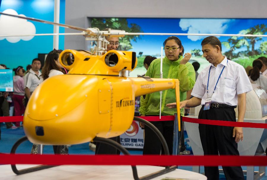 Visitors look at the model of an unmanned helicopter during a science exhibition in Beijing, capital of China, May 19, 2013. The exhibition is a part of the National Science and Technology Week and will last till May 25. (Xinhua/Luo Xiaoguang)