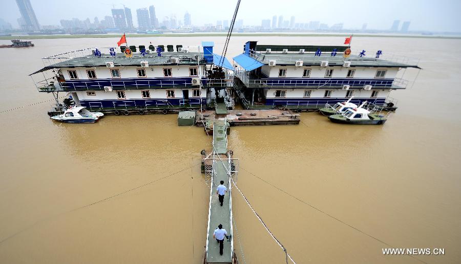 Marine policemen have to board a police vessel through a temporarily-built bridge due to the high water level on the Ganjiang River in Nanchang, capital of east China's Jiangxi Province, May 19, 2013. The rainfall from May 14 has pushed up the water level of the Ganjiang River, which has reached 18.95 meters by 8 a.m. on April 19, the highest level of this year. (Xinhua/Zhou Ke)