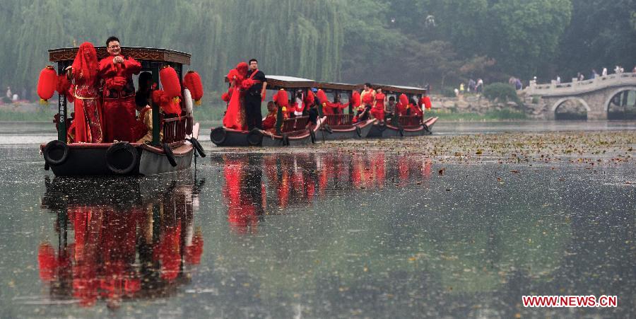 Newlyweds board on boats during a group wedding held in the Old Summer Palace, or Yuanmingyuan park, in Beijing, China, May 18, 2013. A total of 30 couples of newlyweds took part in event with traditional Chinese style here on Saturday. (Xinhua/Luo Xiaoguang) 