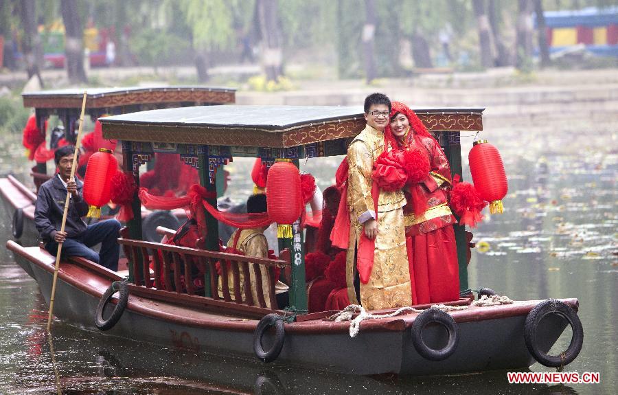 A couple of newlyweds board on a boat during a group wedding held in the Old Summer Palace, or Yuanmingyuan park, in Beijing, China, May 18, 2013. A total of 30 couples of newlyweds took part in event with traditional Chinese style here on Saturday. (Xinhua/Zhao Bing)