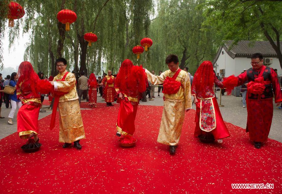 Newlyweds step over "braziers", a symbol of good luck, during a group wedding held in the Old Summer Palace, or Yuanmingyuan park, in Beijing, China, May 18, 2013. A total of 30 couples of newlyweds took part in event with traditional Chinese style here on Saturday. (Xinhua/Luo Xiaoguang) 