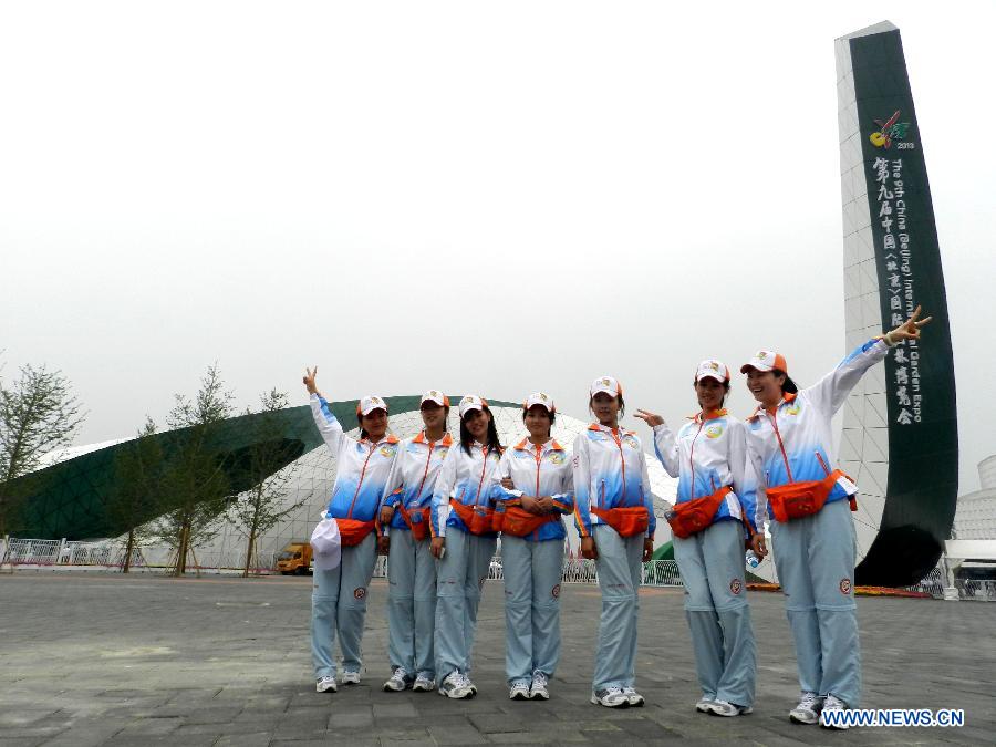 Volunteers pose for group photo at the gate of the garden show park during the 9th China (Beijing) International Garden Expo in Beijing, capital of China, May 18, 2013. The expo opened in southwestern Fengtai district in Beijing on Saturday and will last till Nov. 18, 2013. Garden designs from 69 Chinese cities and 29 countries will be presented. (Xinhua/Wang Zhen)