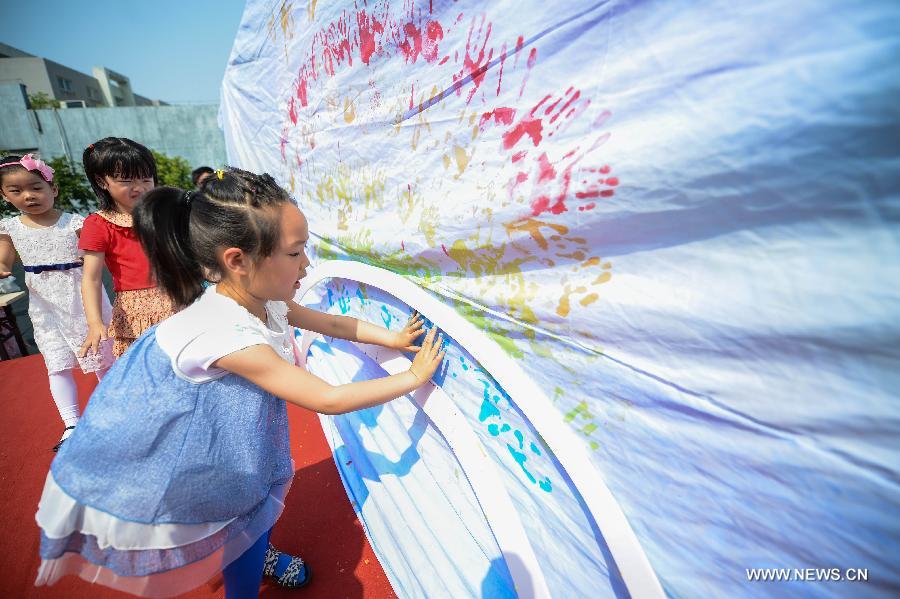 Children press hands with paint to form a rainbow in a kindergarten in Hangzhou, capital of east China's Zhejiang Province, May 21, 2013. An activity for children to present their ideas and creations was held to celebrate the coming Children's Day. (Xinhua/Xu Yu) 