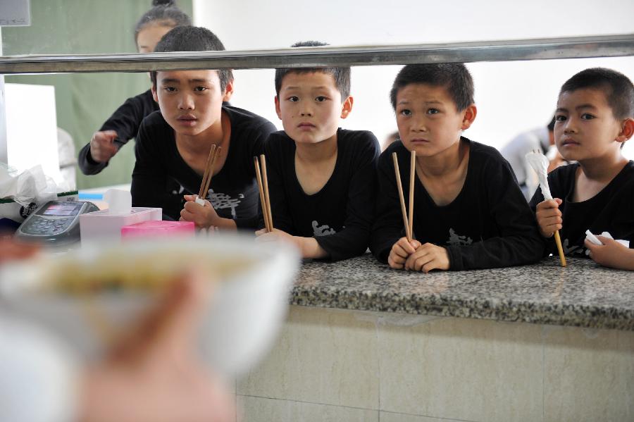 Children of an acrobatic troupe wait for dinner at a canteen in Yinchuan, capital of northwest China's Ningxia Hui Autonomous Region, May 20, 2013. Established in 1958, the acrobatics troupe was now affiliated with Ningxia Yinchuan Art Theatre. During the past few years, over 30 children between 5 and 13 years old have been admitted to the troupe to exercise acrobatics. In order to perform well on the stage, they exert much effort on exercising. Besides, they also learn general courses such as maths, Chinese and English. Yao Xing, deputy principal of the troupe, said that acrobatics requires painstaking effort, which will pay off one day. (Xinhua/Peng Zhaozhi)
