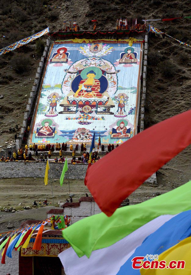 Lamas unfold a huge thangka, a painting on silk with embroidery, at Tsurphu Monastery in Tibet Autonomous Region, May 21, 2013. The Thangka Festival was held on Tuesday, attracting many believers to the monastery to pray, get blessed and appreciate the big and vividly woven thangka. Tsurphu Monastery is the most important monastery of the Karma Kagyu lineage, which is probably the largest and certainly the most widely practiced lineage within the Kagyu school, one of the four major schools of Tibetan Buddhism. [Photo: CNS/Li Lin]