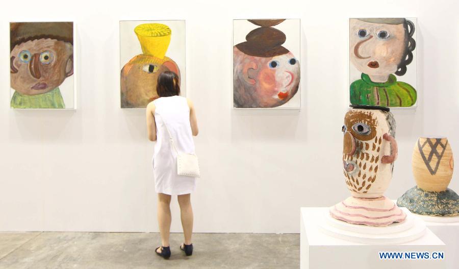 A woman stops in front of painting works during the exhibition Art Basel in Hong Kong, in south China's Hong Kong, May 22, 2013. Art Basel in Hong Kong, the latest leg of the international circuit, will kick off here on Thursday. (Xinhua/Lui Siu Wai) 