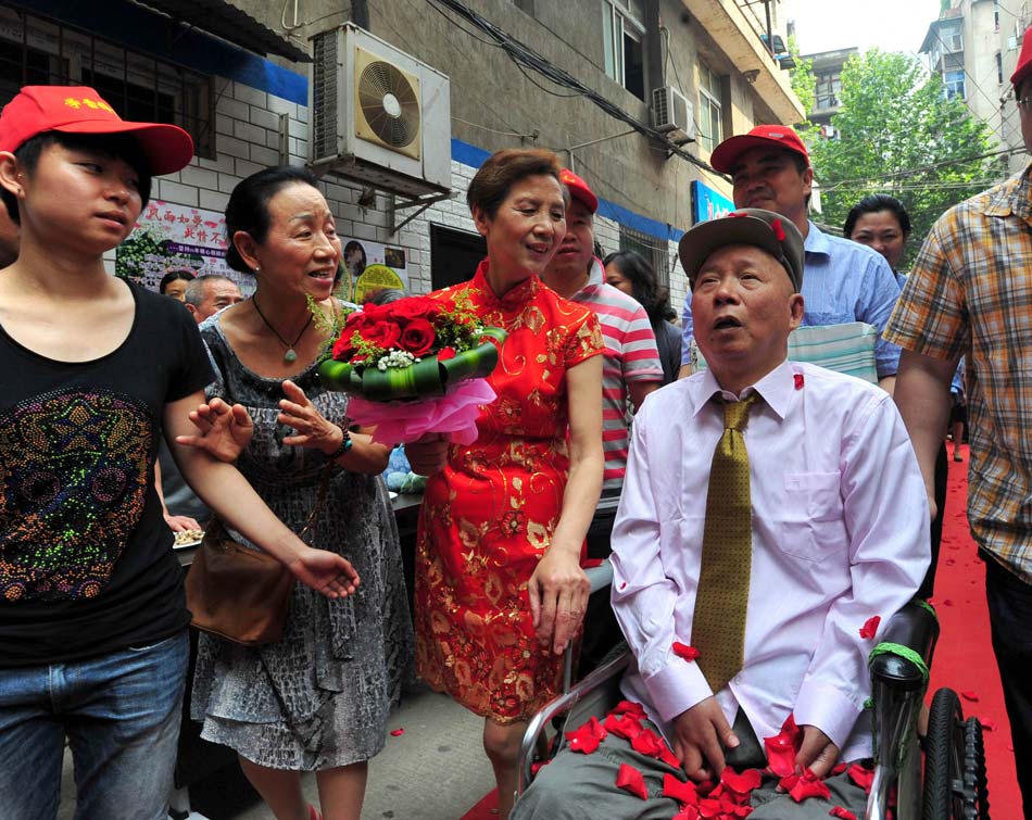 Neighbors throw rose petals after the couple, Wang Mingfang and Tang Shaodou, finally get married in Wuhan, Central China's Hubei province, on May 21. (Photo/ Xinhua)