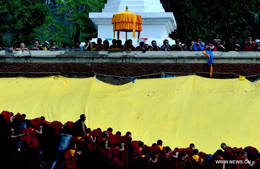 Monks and disciples attend a Buddhist ritual displaying a gigantic Buddha tangka for worship at the Kumbum Monastery, northwest China's Qinghai Province, May 24, 2013. (Xinhua/Wang Bo)