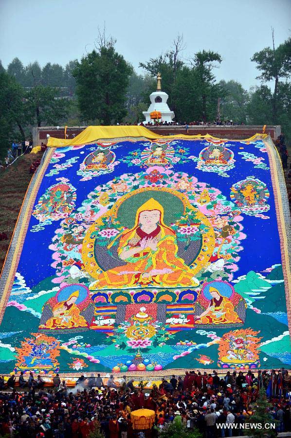 A gigantic Buddha tangka is unveiled alongside a hillside for disciples' worship during a Buddhist ritual at the Kumbum Monastery, northwest China's Qinghai Province, May 24, 2013. (Xinhua/Wang Bo)