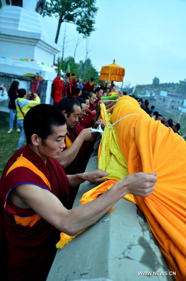 Monks prepare to unveil a gigantic Buddha tangka alongside a hillside for disciples' worship during a Buddhist ritual at the Kumbum Monastery, northwest China's Qinghai Province, May 24, 2013. (Xinhua/Wang Bo)