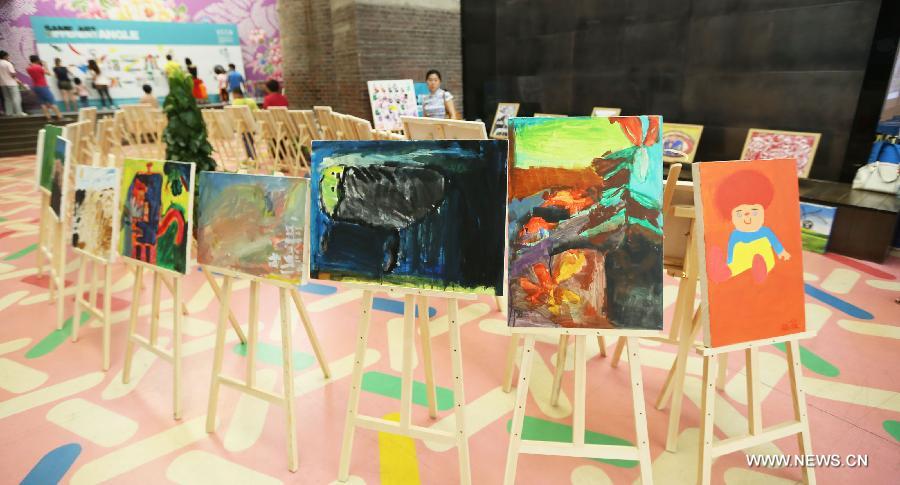 Visitors view paintings at a painting exhibition at the 798 art area in Beijing, capital of China, May 25, 2013. A two-day exhibition kicked off on Saturday, displaying paintings created by over 20 mentally retarded children from Chaoyang Anhua School. (Xinhua)