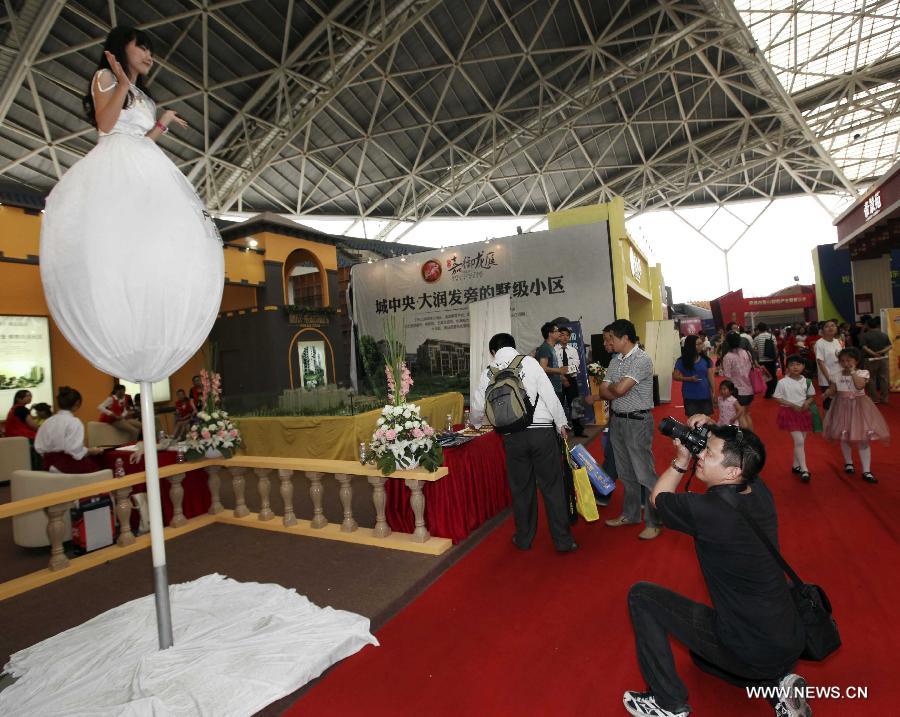 A photographer takes photos of a model who stands on a pole at the 55th house fair in Nantong, east China's Jiangsu Province, May 25, 2013. Eye-catching models highlighted the fair here. (Xinhua/Xu Peiqin)