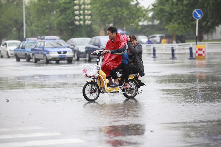 People ride on the street during the rainfall in Heze City, east China's Shandong Province, May 26, 2013. A heavy rainfall hit Shandong Province from May 25 to 26. (Xinhua/Zhou Donglun) 