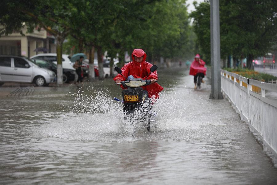 People ride on the street during the rainfall in Heze City, east China's Shandong Province, May 26, 2013. A heavy rainfall hit Shandong Province from May 25 to 26. (Xinhua/Zhou Donglun)