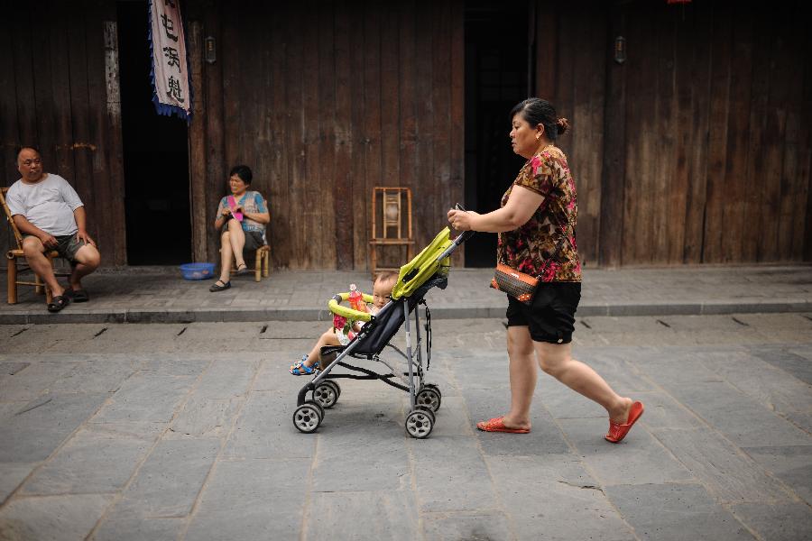 A woman with a baby walks on a street in Anren, an ancient town in Dayi County of Chengdu, capital of southwest China's Sichuan Province, May 23, 2013. Anren Town was first built in ancient China's Tang Dynasty (618-907). Most of its buildings were constructed in late Qing Dynasty (1644-1911) and early Republic of China (1911-1949). Chengdu will host the Global Fortune Forum, an event to be organized by the American magazine "Fortune", on June 6-8. (Xinhua/Shen Hong) 