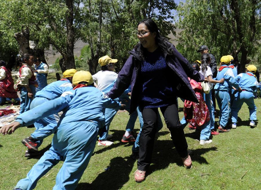 A government staff plays games with children to celebrate the upcoming Children's Day at Qupu Village in Quxu County, southwest China's Tibet Autonomous Region, May 27, 2013. (Xinhua/Chogo)