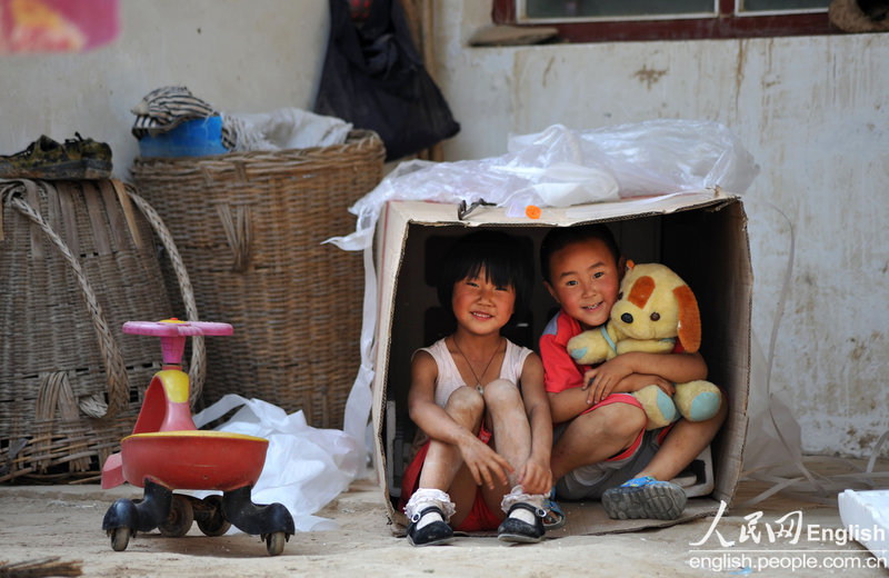 Girls play in the "home" made of a cardboard box for fridge in the yard in a village in Shanxi province. (Photo/ CFP)