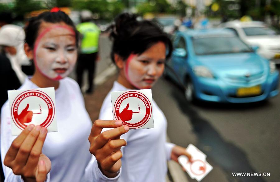 Two performers from Komunitas Kretek, or the Cigarette Community, show stickers on the World No Tobacco Day in Jakarta, Indonesia, May 31, 2013. Indonesian cigarette community refused commemoration of the World No Tobacco Day on May 31. About 70 percent of adult males smoke in Indonesia. (Xinhua/Agung Kuncahya B.) 