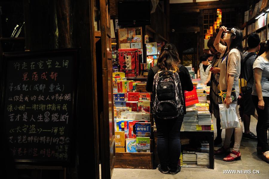 People choose to buy books in a bookstore on the Kuan Zhai Xiang Zi, or the Wide and Narrow Alleys in Chengdu, capital of southwest China's Sichuan Province, May 31, 2013. Consisting of three remodeled historical community alleyways dating back to the Qing Dynasty, the Wide and Narrow Alleys are now bordered with exquisitely decorated tea houses, cafes, boutiques and bookshops. The 2013 Fortune Global Forum will be held in Chengdu from June 6 to June 8. Chengdu, a city known for its slow living pace, is developing into an international metropolis with its huge economic development potential as well as its special cultural environment. (Xinhua/Li Hualiang)