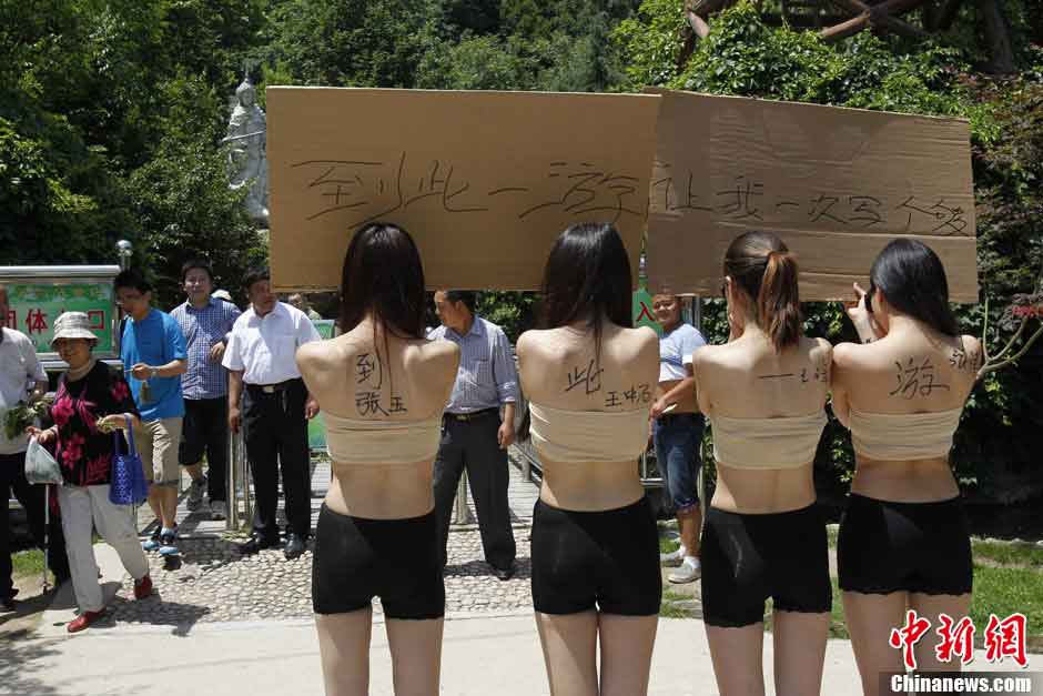 Four women hold boards with words demanding for a special place where the tourists can sign their signitures at will in Yangzigou scenic spot, in centeral China's Henan Province, June 2, 2013. (Source: chinanews.com)  