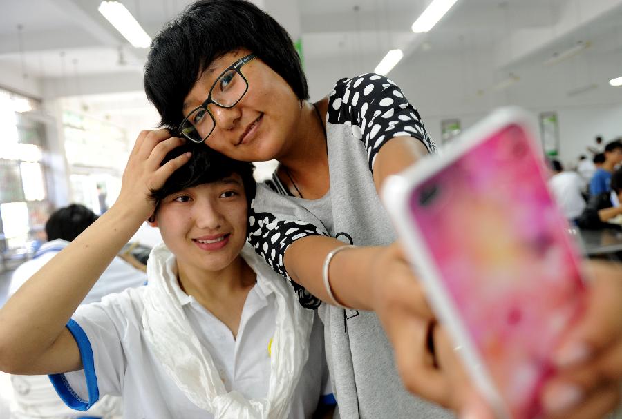 Photo shows two classmates in the inland Tibetan class take photos as momento before they leave for hometown on June 4, 2013. Having finished their study in the inland Tibetan class, the 181 Tibetan students will go back to Tibet for the upcoming national high school entrance examination, reported by Xinhua. [Photo/Xinhua]