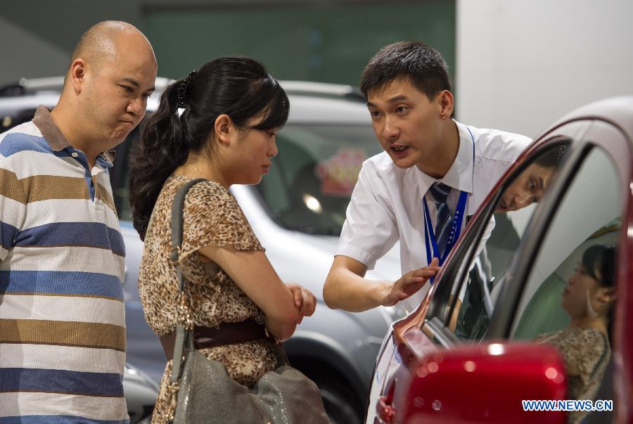 A staff member introduces a car to visitors at the 15th Chongqing International Auto Industry Fair in Chongqing, southwest China's municipality, June 7, 2013. Opened Friday, the week-long fair attracts 105 domestic and foreign exhibitors and will launch 60 new models. (Xinhua/Chen Cheng)