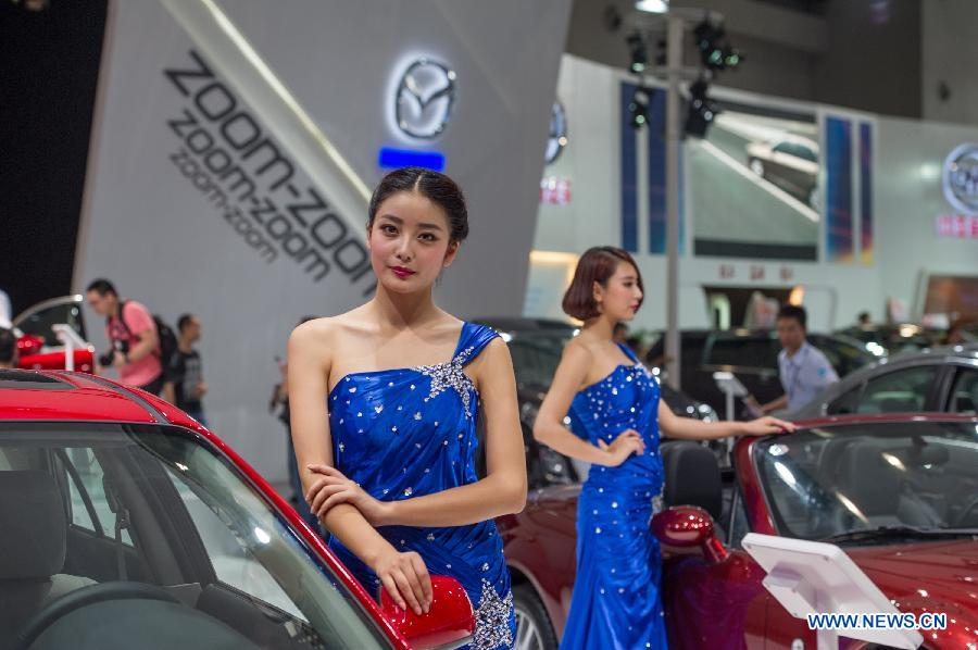 Models pose beside cars at the 15th Chongqing International Auto Industry Fair in Chongqing, southwest China's municipality, June 7, 2013. Opened Friday, the week-long fair attracted 105 domestic and foreign exhibitors and will launch 60 new models. (Xinhua/Chen Cheng)