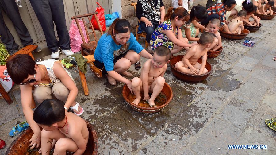 Mothers bath their children using moxa leaf water during an event at Guizhou Township in Zigui County, cental China's Hubei Province, June 7, 2013. People in Zigui, the hometown of Qu Yuan, prepare to celebrate the upcoming Dragon Boat Festival, or Duanwu Festival, which falls on the fifth day of the fifth month in the Chinese lunar calendar, or June 12 this year. The festival is to commemorate the death of Qu Yuan, a patriot poet during the Warring States Period (475-221B.C.), who committed suicide by flinging himself into the Miluo River after his mother kingdom, fell into enemy's hands. (Xinhua/Zheng Jiayu)