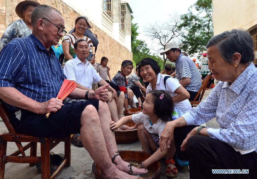 A child washes feet for an old man using moxa leaf water during an event at Guizhou Township in Zigui County, cental China's Hubei Province, June 7, 2013. People in Zigui, the hometown of Qu Yuan, prepare to celebrate the upcoming Dragon Boat Festival, or Duanwu Festival, which falls on the fifth day of the fifth month in the Chinese lunar calendar, or June 12 this year. The festival is to commemorate the death of Qu Yuan, a patriot poet during the Warring States Period (475-221B.C.), who committed suicide by flinging himself into the Miluo River after his mother kingdom, fell into enemy's hands. (Xinhua/Zheng Jiayu)