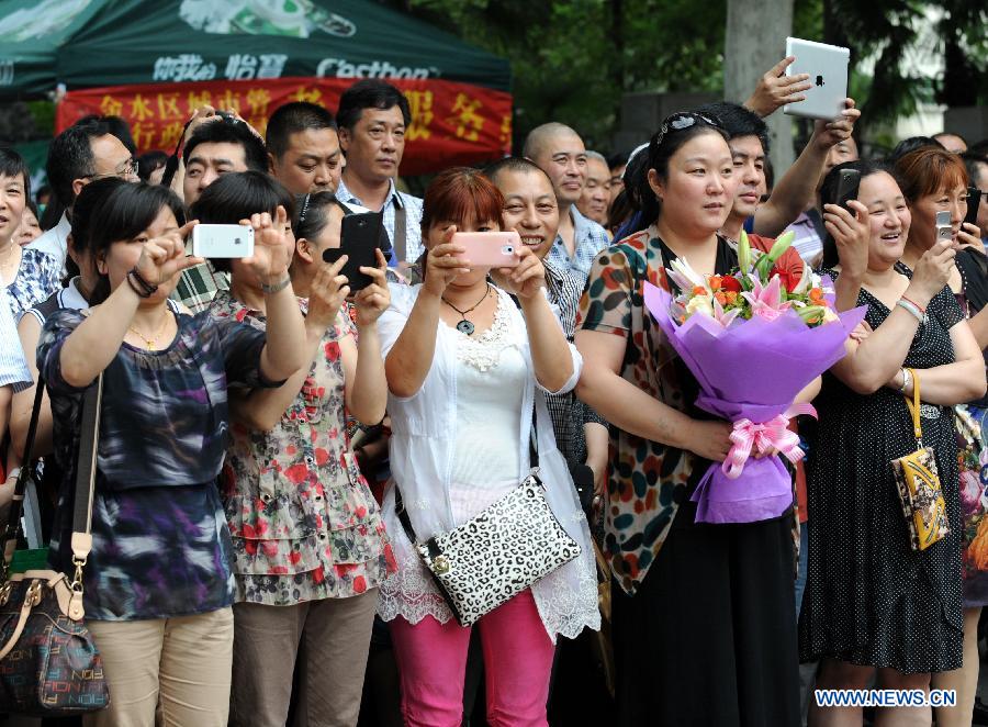Parents wait outside the Huimin Middle School in Zhengzhou, capital of central China's Henan Province, June 8, 2013. The 2013 national college entrance examination ended in some regions of China on Saturday. Approximately 9.12 million people took part in the exam this year. (Xinhua/Li Bo)