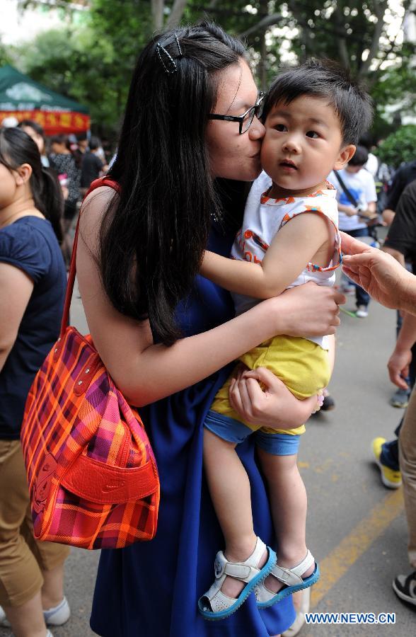 A student kisses her nephew after the college entrance examination in Huimin Middle School in Zhengzhou, capital of central China's Henan Province, June 8, 2013. The 2013 national college entrance examination ended in some regions of China on Saturday. Approximately 9.12 million people took part in the exam this year. (Xinhua/Li Bo) 