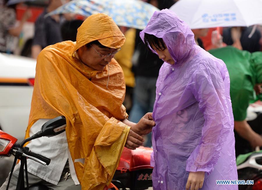 A father puts on a raincoat for his daughter outside the Xi'an No. 1 Middle School in Xi'an, capital of northwest China's Shaanxi Province, June 8, 2013. The 2013 national college entrance examination ended in some regions of China on Saturday. Approximately 9.12 million people took part in the exam this year. (Xinhua/Li Yibo)