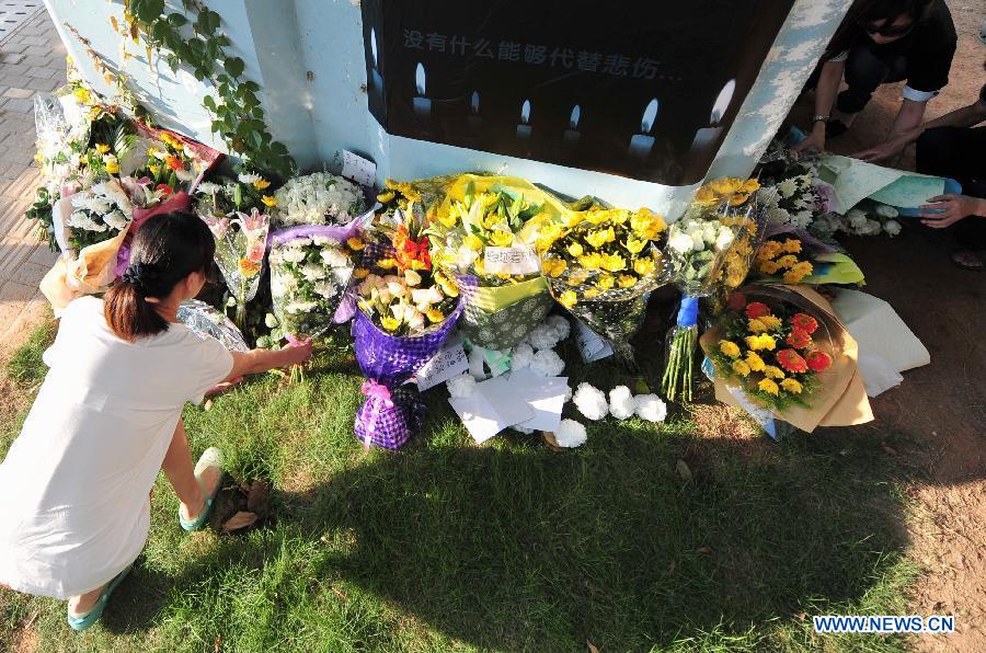 A woman lays flowers to mourn for the victims in front a pier of the elevated bus lane where a bus fire took place on Friday, in Xiamen, southeast China's Fujian Province, June 8, 2013. The bus fire has claimed 47 lives and hospitalized 34 passgengers. (Xinhua/Wei Peiquan)