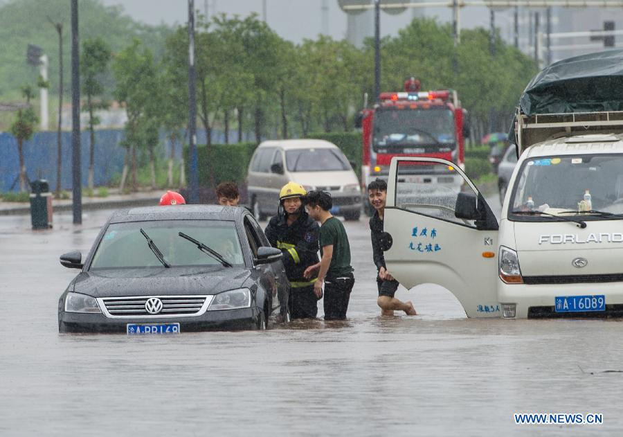Firefighters help move a car trapped on a waterlogged road in southwest China's Chongqing Municipality, June 9, 2013. Heavy rainfall hit Chongqing as the city issued a red rainstorm warning here on Sunday. (Xinhua/Chen Cheng) 