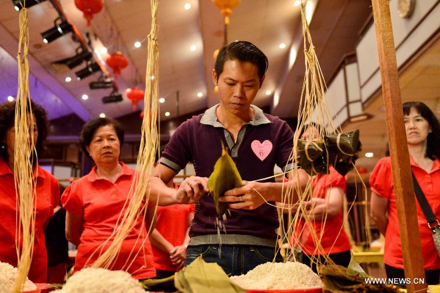 A contestant makes Zongzi, a pyramid-shaped dumpling made of glutinous rice wrapped in bamboo or reed leaves, during a contest in celebration of the upcoming Dragon Boat Festival in Kuala Lumpur, Malaysia, June 9, 2013. The contest was held by a local Chinese association to promote the traditional Chinese festival -- Dragon Boat Festival, which falls on the fifth day on the fifth month on the lunar calendar. (Xinhua/Chong Voon Chung)