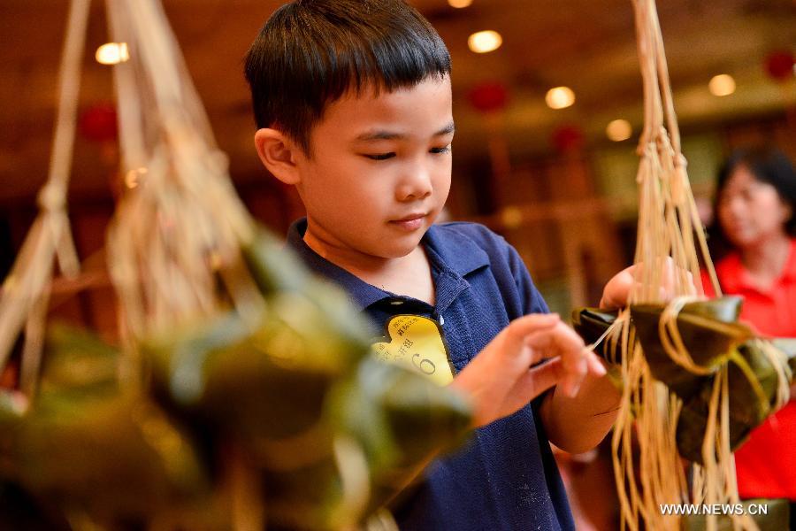 A 6-year-old contestant makes Zongzi, a pyramid-shaped dumpling made of glutinous rice wrapped in bamboo or reed leaves, during a contest in celebration of the upcoming Dragon Boat Festival in Kuala Lumpur, Malaysia, June 9, 2013. The contest was held by a local Chinese association to promote the traditional Chinese festival -- Dragon Boat Festival, which falls on the fifth day on the fifth month on the lunar calendar. (Xinhua/Chong Voon Chung)