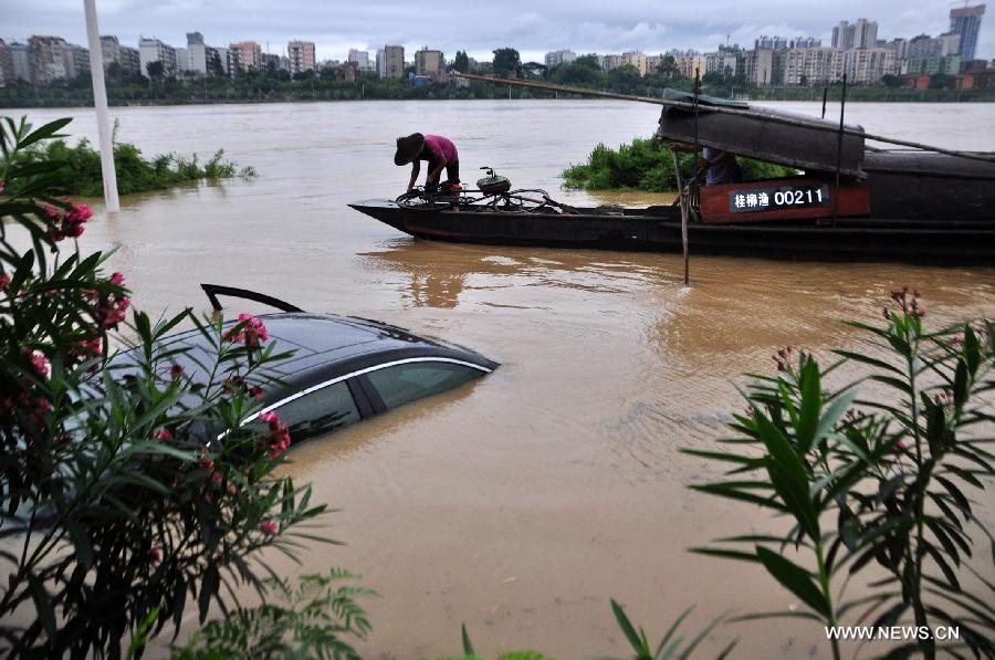 A fishing boat passes by a trapped vehicle on a flooded road in Liuzhou City, south China's Guangxi Zhuang Autonomous Region, June 10, 2013. Lingering heavy rainfalls in recent days has caused the Liujiang River's water level to rise to 82.7 meters in urban Liuzhou by 11 a.m. Beijing Time (0300 GMT) on Monday, 0.2 meters higher than the warning level. (Xinhua/Li Shuhou) 