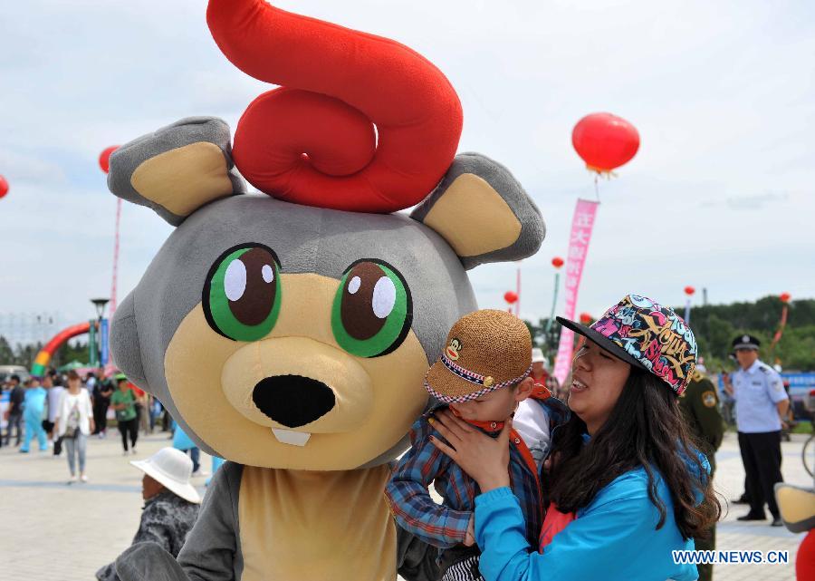 The volcano mascot of the traditional "Holy Water Festival" poses for photo with tourists in Wudalianchi, northeast China's Heilongjiang Province, June 11, 2013. The festival was listed as the National Intangible Cultural Heritage in 2010. (Xinhua/Wang Jianwei) 
