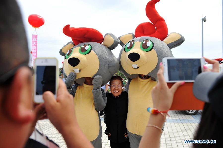 The volcano mascots of the traditional "Holy Water Festival" pose for photo with a tourist in Wudalianchi, northeast China's Heilongjiang Province, June 11, 2013. The festival was listed as the National Intangible Cultural Heritage in 2010. (Xinhua/Wang Jianwei) 