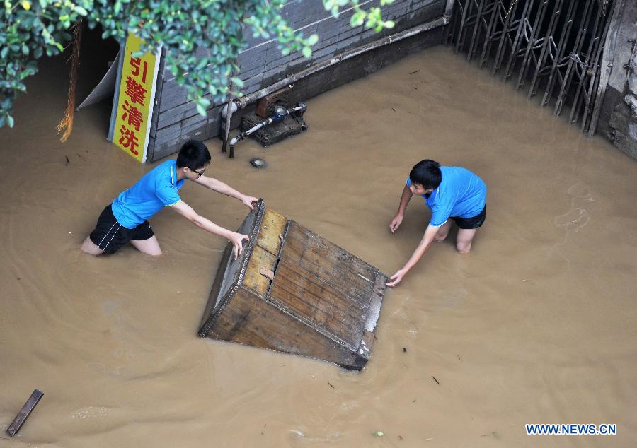 People carry a cabinet in a flooded street in Liuzhou City, south China's Guangxi Zhuang Autonomous Region, June 11, 2013. Liujiang River's water level surpassed the warning line in urban Liuzhou on Monday, and started to descend in the night after the flood peak. (Xinhua/Li Bin)
