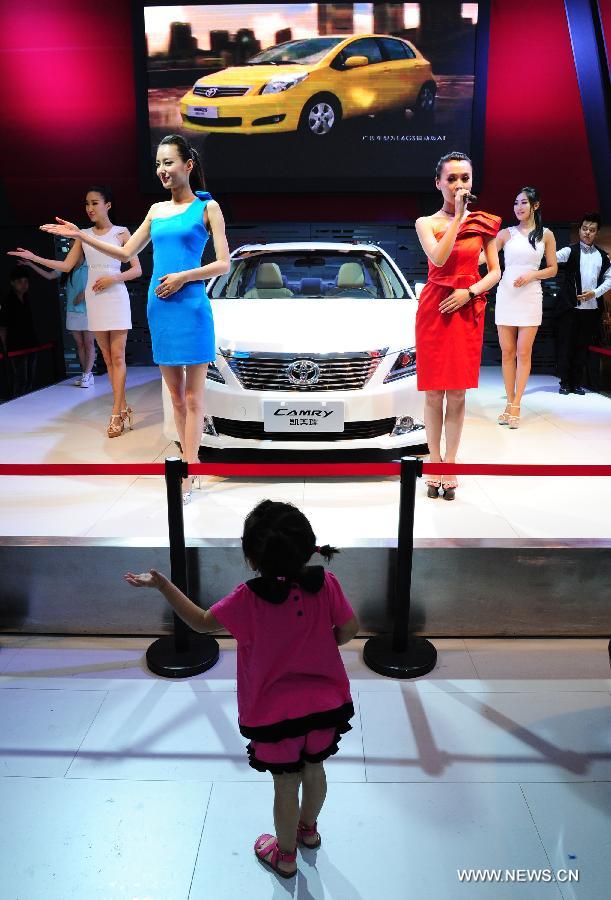 A little girl imitates gestures of models at 2013 Xi'an International Automobile Industry Exposition in Xi'an, capital of northwest China's Shaanxi Province, June 12, 2013. Visiting the auto show, which lasts from June 8 to 17, is the way many local residents spent their three-day Dragon Boat Festival vacation from June 10 to 12. (Xinhua/Ding Haitao)