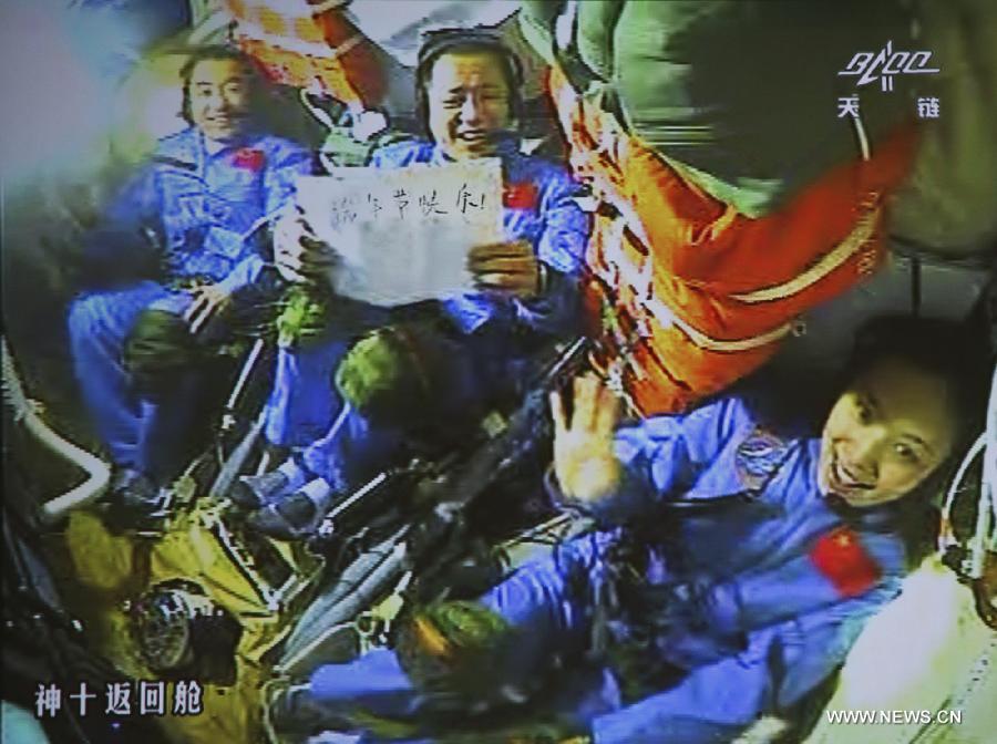 This video grab taken from the screen at the Beijing Aerospace Control Center shows Chinese astronauts on the Shenzhou-10 spacecraft greeting the nation and the Chinese in the global for the Dragon Boat Festival, on June 12, 2013. The words on the paper read "Happy Dragon Boat Festival!" (Xinhua/Wang Sijang)