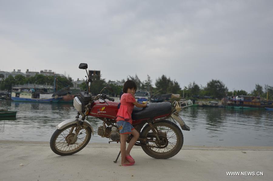 A girl rests beside the autocycle of her father at Tanmen port of Tanmen Town in Qionghai City, south China's Hainan Province, June 12, 2013. (Xinhua/Pan Chaoyue)