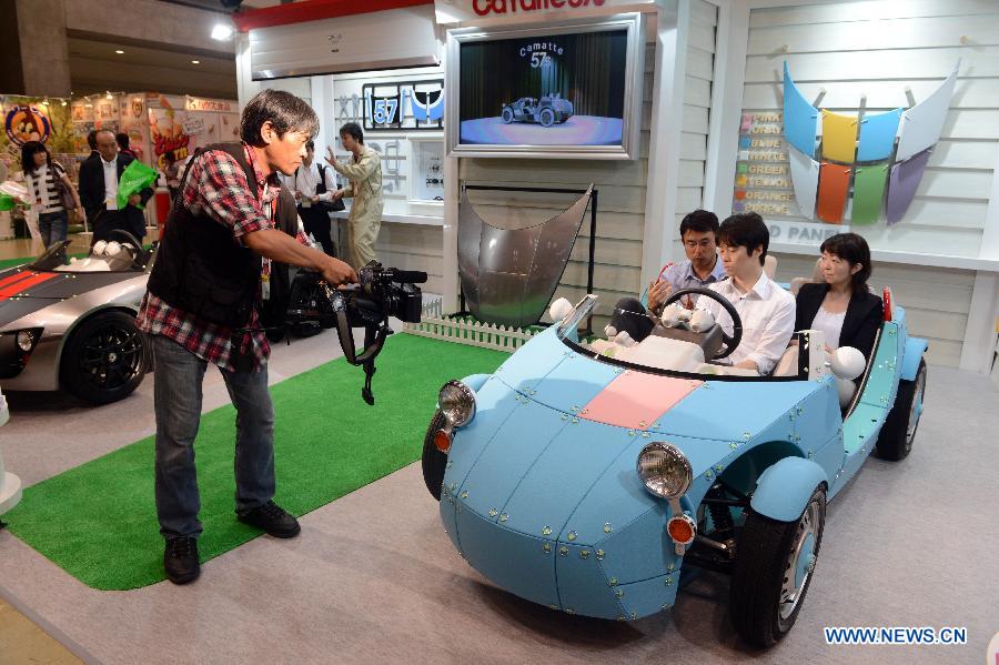 Visitors try a Toyota Motor's concept model of a three-seater electric vehicle called the "Camatte 57S" at the annual International Tokyo Toy Show on June 13, 2013. The International Toy Show kicked off here on Thursday. (Xinhua/Ma Ping)