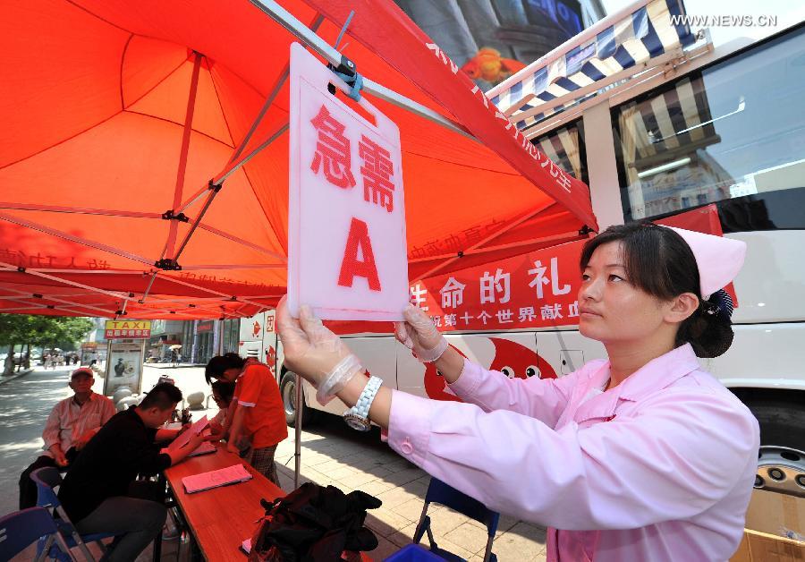 A medical staff member hangs a notice to encourage people to donate blood in urgent need in a voluntary blood donation house in Yinchuan, capital of Ningxia Hui Autonomous Region, June 14, 2013. June 14 is the World Blood Donor Day. Many citizens in Yinchuan donated their blood for free on the streets of Yinchuan on Friday. (Xinhua/Peng Zhaozhi) 