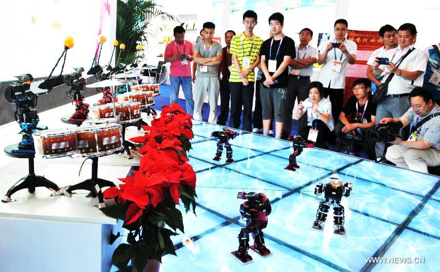 Visitors watch the performance of robots at the 24th China Harbin International Economic and Trade Fair in Harbin, capital of northeast China's Heilongjiang Province, June 15, 2013. A total of 9,335 exhibitors from 75 countries and regions took part in the fair. (Xinhua/Wang Jianwei)