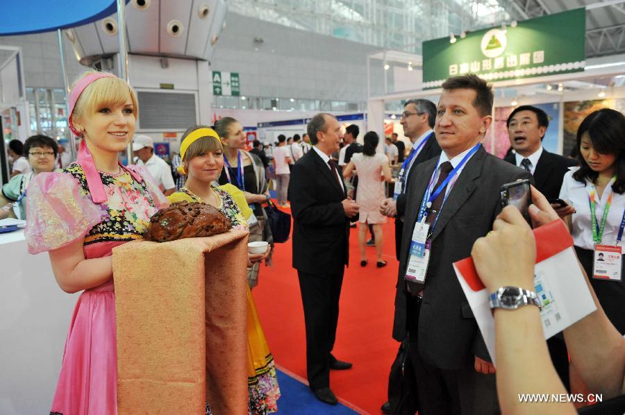 A Russian girl shows Russian bread to greet visitors at the 24th China Harbin International Economic and Trade Fair in Harbin, capital of northeast China's Heilongjiang Province, June 15, 2013. A total of 9,335 exhibitors from 75 countries and regions took part in the fair. (Xinhua/Wang Jianwei)